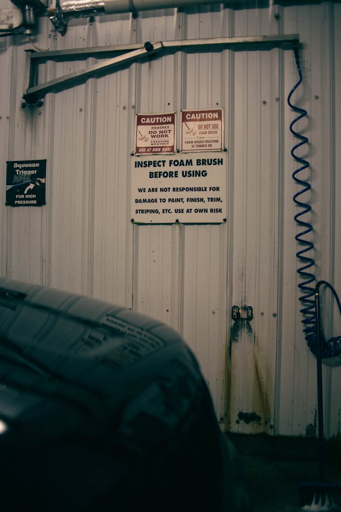 An indoor car garage scene with caution and warning signs on the wall.